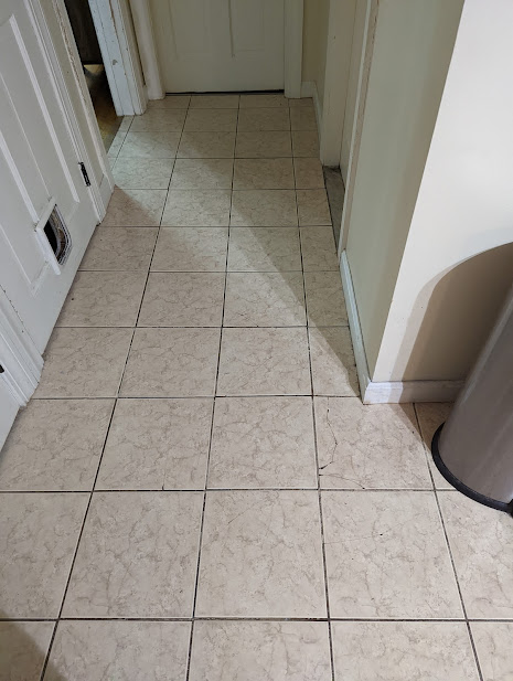 Old kitchen floor with cracked tiles and missing grout.